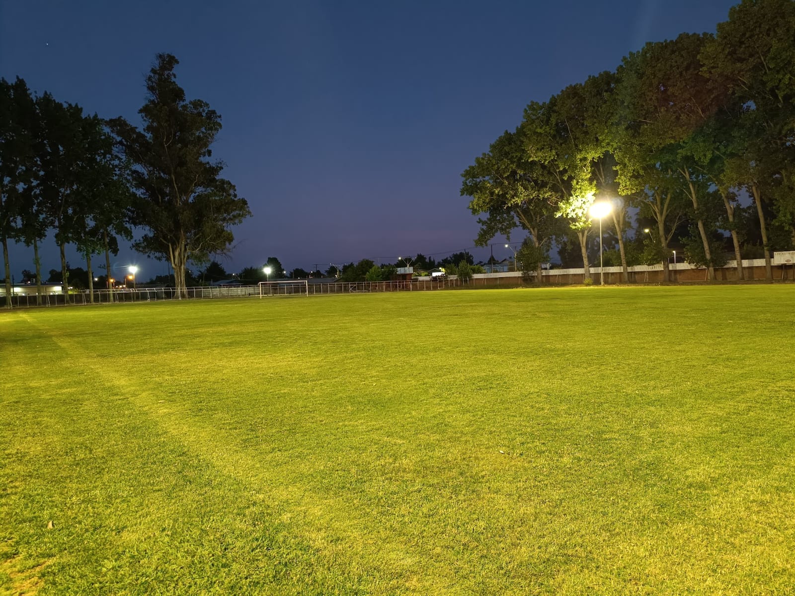 Cancha de fútbol iluminada en Linares al anochecer